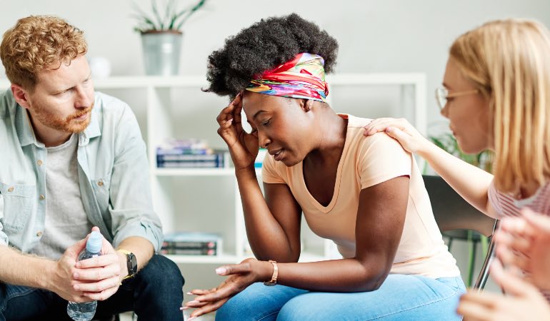 Woman being consoled in group therapy