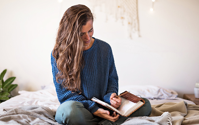 lady sitting on her bed writing in her journal